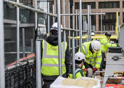 Image of building that Deep Group London provided cladding scaffolding services for. The construction works are working on the building. They are wearing hi-vis jackets that say Deep Group on the back